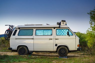 Camper van with internal thermal screen blind at window pane camping on nature in summer. Vanlife. Caravan vacation. clipart