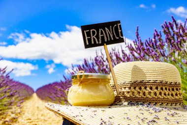Yaz şapkası, ballı kavanoz ve üzerinde taze lavanta tarlası arka planına karşı Fransa imzası olan tabela. Provence 'de Fransız tatili için çekim gezisi.