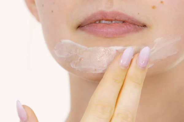 stock image Young woman applying cream cosmetic, mask moisturizing to her face. Beauty treatment. Skincare.