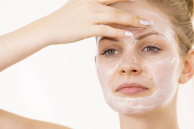 Genç bir kadın krem kozmetik uyguluyor, yüzüne nemlendirici maske takıyor. Güzellik tedavisi. Cilt bakımı.