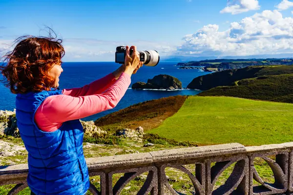 Kameralı kadın Atlantik Okyanusu 'nun deniz manzarasından ve İspanya' nın kuzeyindeki Penas Burnu 'ndaki Asturias sahilinden seyahat fotoğrafı çekiyor..