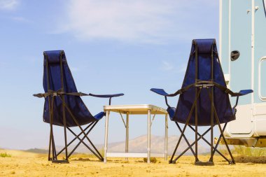 Camp equipment chairs and table at caravan. Wild camping on nature. Holidays and traveling in motor home.