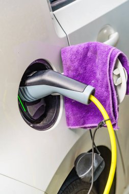 Şarj istasyonunda elektrik prizi olan elektrikli bir araba. Ekolojik ulaşım. Otomotiv teknolojisi kavramı.