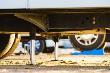 Kamp için otomatik seviye sistemi. Hidrolik sabit bacak kullanımda. Arkadaki karavan için mavi rampa tıkanıklığı.