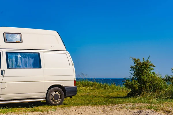 Camper van camping on sea shore in summer. Traveling by motor home. Caravan vacation.