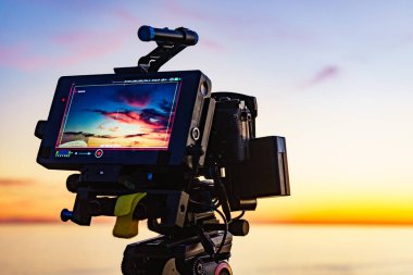 Profesyonel kamera tripodun üzerinde gün batımının görüntülerini çekiyor..