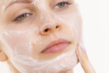 Genç bir kadın krem kozmetik uyguluyor, yüzüne nemlendirici maske takıyor. Güzellik tedavisi. Cilt bakımı.