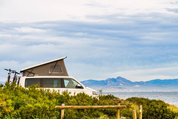 Van camper with roof top tent camping on mediterranean coast. Holidays and travel in mobile home. Van life.