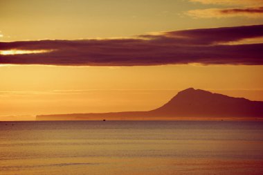 Denizde gün doğumu. Montgo Dağı silueti ufukta görünüyor. Gandia, Valencia İspanya yakınlarındaki plajdan görüntü