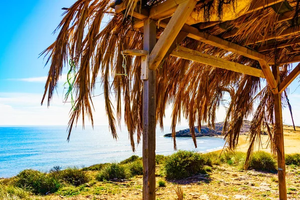 Mediterranean sea coast landscape, beach with shelter made of palm leaves, Murcia region, Calblanque Regional Park in Spain.
