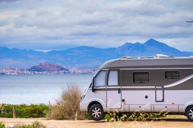 Akdeniz kıyısındaki karavan, uzakta Alicante şehri, Costa Blanca İspanya. Kumsalda vahşi bir kamp. Karavanla tatil gezisi..