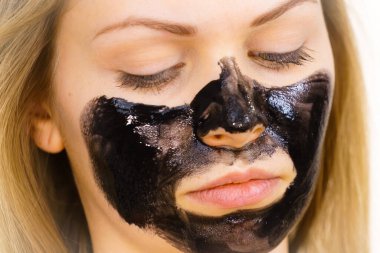 Yüzüne karbonhidrat maskesi takan genç bir kadın. Genç kız yağlı cildiyle ilgileniyor, gözenekleri temizliyor. Spa tedavisi. Cilt bakımı.