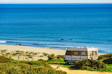 Camper rv caravan on mediterranean coast in Spain. Wild camping on sea shore. Holidays trip with motor home.