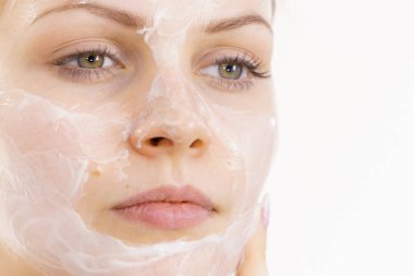 Genç bir kadın krem kozmetik uyguluyor, yüzüne nemlendirici maske takıyor. Güzellik tedavisi. Cilt bakımı.