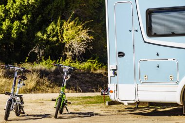 Camper, recreational vehicle and two electric bicycles. Camping on nature. Holidays and travel in motorhome.