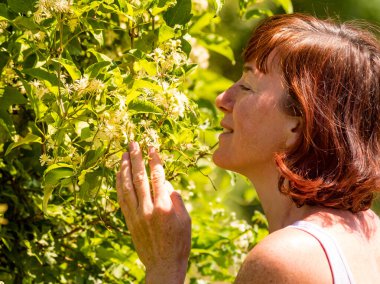 Beyaz çiçek kokan bir kadın. Olgun bir kadın doğanın tadını çıkarıyor.