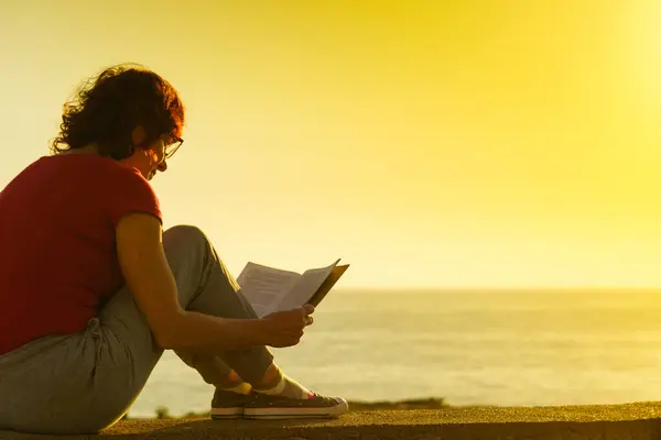 관광객인 여자는 해안에서 가지고 휴식을 취하며 공기를 즐긴다 휴일에 읽는다 로열티 프리 스톡 사진