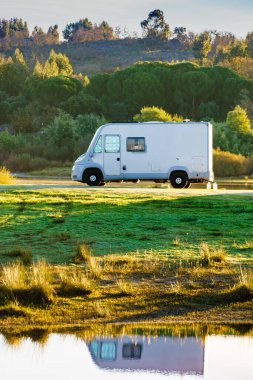 Camping on nature. Camper vehicle at lake shore reflecting in water. Povoa e Meadas Dam in Castelo de Vide, Alentejo Portugal. Travel in motor home. clipart