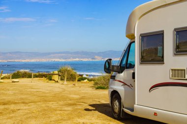 Caravan on mediterranean coast, Alicante city in the distance, Costa Blanca Spain. Wild camping on beach. Vacation trip with motor home.
