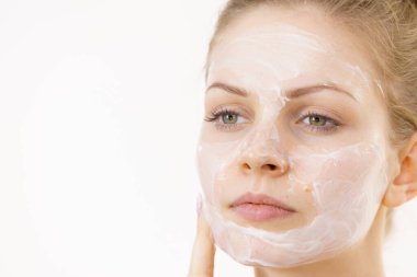 Genç bir kadın krem kozmetik uyguluyor, yüzüne nemlendirici maske takıyor. Güzellik tedavisi. Cilt bakımı.