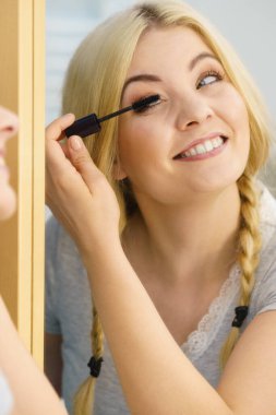 Makyajını siyah rimel sürerek yapan bir kadın kirpiklerini fırçalıyor. Kadın güzellik çehresi konsepti.