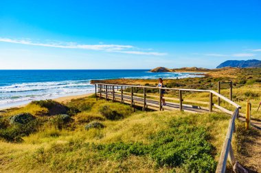 Sahilde dinlenen, gün ışığının tadını çıkaran turist bir kadın. Calblanque Bölgesel Parkı 'nda Cala Magre, Murcia bölgesi İspanya.