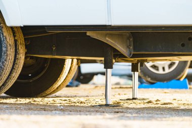 Kamp için otomatik seviye sistemi. Hidrolik sabit bacak kullanımda. Arkadaki karavan için mavi rampa tıkanıklığı.