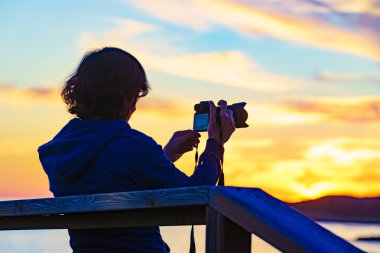 Kameralı turist kadın gün batımında doğada fotoğraf çekiyor..