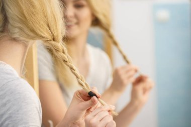 Genç, güzel sarışın kadın saç modelini yapıyor, örgü örüyor. Güzel bayan hazırlanıyor.