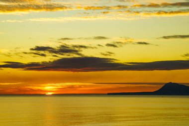 Denizde gün doğumu. Montgo Dağı silueti ufukta görünüyor. Gandia, Valencia İspanya yakınlarındaki plajdan görüntü