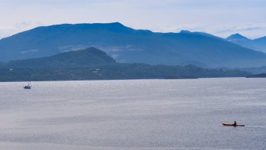 Atlantik okyanusunda kanoyla kanoya binen insanlar. Dağlar manzara uzakta. Turizm tatil ve seyahat.