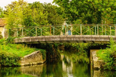 Coulon town in France. River view with old stone bridge. Deux Sevres, New Aquitaine region. Tourism place clipart