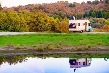 Doğada kamp yapmak. Göl kıyısındaki kamp aracı suya yansıyor. Povoa e Meadas Barajı, Castelo de Vide, Alentejo Portekiz. Karavanla git..