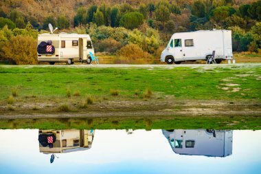 Doğada kamp yapmak. Göl kıyısındaki kamp araçları suya yansıyor. Povoa e Meadas Barajı, Castelo de Vide, Alentejo Portekiz. Karavanla git..