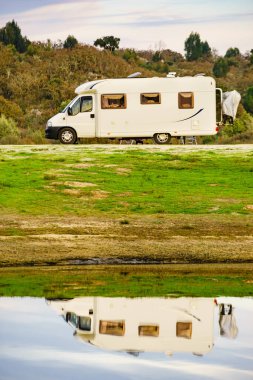 Doğada kamp yapmak. Göl kıyısındaki kamp aracı suya yansıyor. Povoa e Meadas Barajı, Castelo de Vide, Alentejo Portekiz. Karavanla git..