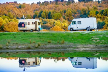 Doğada kamp yapmak. Göl kıyısındaki kamp araçları suya yansıyor. Povoa e Meadas Barajı, Castelo de Vide, Alentejo Portekiz. Karavanla git..