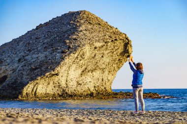 Cabo de Gata Nijar Doğal Parkı 'nda Monsul sahilinde yürüyen bir kadın. Almerya kıyıları. Turist çekmek için büyük lav oluşumu.