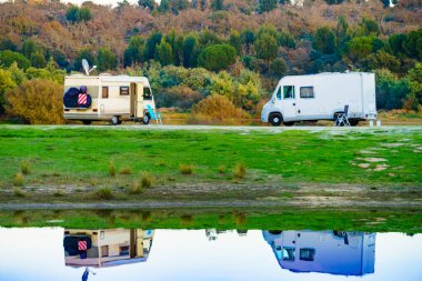 Doğada kamp yapmak. Göl kıyısındaki kamp araçları suya yansıyor. Povoa e Meadas Barajı, Castelo de Vide, Alentejo Portekiz. Karavanla git..