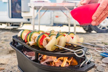 Izgara ızgarada çeşit çeşit lezzetli sebze şişleri. Barbekü yemeği dışarıda. Arka planda karavan var..