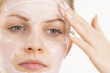 Genç bir kadın krem kozmetik uyguluyor, yüzüne nemlendirici maske takıyor. Güzellik tedavisi. Cilt bakımı.