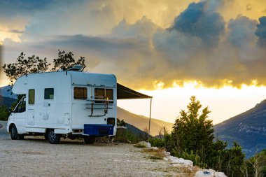 Kapalı tenteli bir kamp aracı ve Fransız dağlarında sandalyeli bir turist masası. Doğada kamp yapmak. Tatiller ve karavanla seyahat.