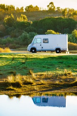 Doğada kamp yapmak. Göl kıyısındaki kamp aracı suya yansıyor. Povoa e Meadas Barajı, Castelo de Vide, Alentejo Portekiz. Karavanla git..
