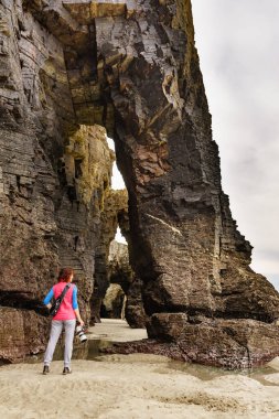 Galiçya 'daki Katedral Plajı' ndaki uçurum oluşumlarından fotoğraf çeken turist kadın. Playa de las Catedrales, Kuzey İspanya 'nın Ribadeo eyaletinde Katedrais Olarak.