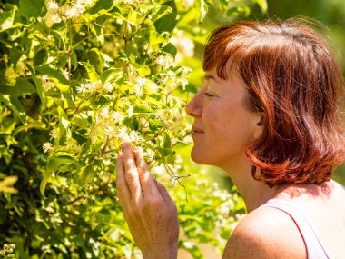 Beyaz çiçek kokan bir kadın. Olgun bir kadın doğanın tadını çıkarıyor.