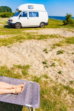 Güverte sandalyesinde kadın ayakları. Güneşli yaz gününde karavanın önünde güneşlenen kadın dinleniyor...