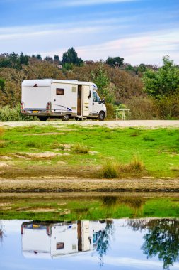 Doğada kamp yapmak. Göl kıyısındaki kamp aracı suya yansıyor. Povoa e Meadas Barajı, Castelo de Vide, Alentejo Portekiz. Karavanla git..