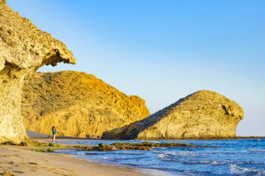 Cabo de Gata Nijar Doğal Parkı 'ndaki Monsul sahilinde yürüyen insanlar. Almerya kıyıları. Turist çekmek için büyük lav oluşumu.