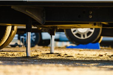 Kamp için otomatik seviye sistemi. Hidrolik sabit bacak kullanımda. Arkadaki karavan için mavi rampa tıkanıklığı.