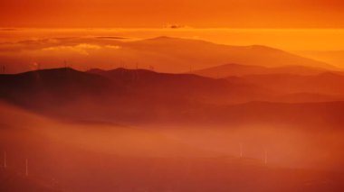 Rüzgar türbinleri gün batımında bulutların üzerinde. Portekiz 'deki Torre Dağı tepesinden Serra da Estrela' nın görüntüsü.