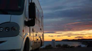 Gün batımında deniz kenarında kamp yapan bir karavan. Karavanla seyahat ediyorum. Karavan tatili. Doğa ve faaliyetler.